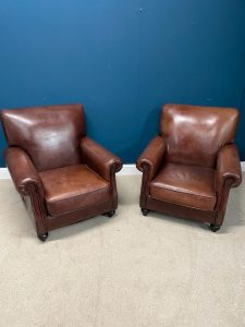 Pair of leather upholstered club chairs raised on bun feet
