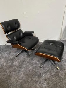 Black leather Eames chair with matching stool raised on chrome base